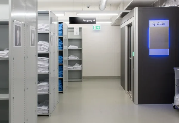 A unmanned storage area in a hospital. There is a Q-Gate standing with a blue sign that says Q-Gate. It´s an advanced logistics system for inventory management in unmanned storage areas.