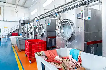Stora industri tvättmaskiner på rad. Tvätteri som tvättar textilier arbetskläder märkta med RFID transpondrar.